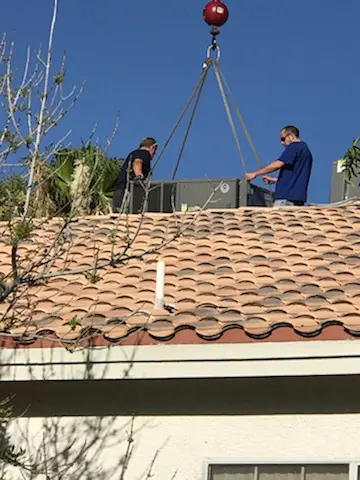 Crew using crane to place HVAC equipment on roof
