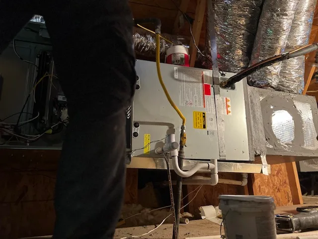HVAC technician servicing attic furnace and air handler